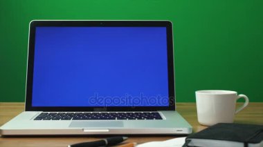 Yeşil ekran ve tablo üzerinde siyah Not Defteri ile dizüstü bilgisayar. Yeşil ekran arka planı
