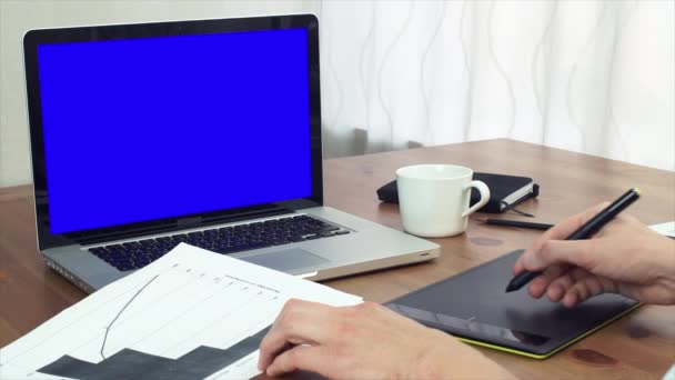 Jeune homme travaillant avec des graphiques d'analyse imprimés utilisant une tablette numérique et un ordinateur portable — Video