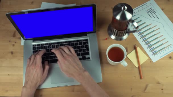 Bovenaanzicht mannelijke handen werken met gedrukte grafieken laptop met groen scherm — Stockvideo