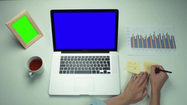 Pohled shora mužské ruce pomocí poznámek sticky notes a laptop s zelená obrazovka — Stock video