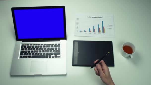 Bovenaanzicht mannelijke handen met behulp van grafische tabblad en laptop met groen scherm op witte Bureau — Stockvideo