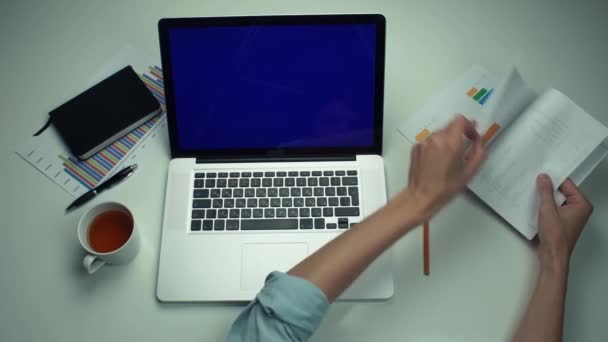 Pohled shora mužské ruce pomocí grafické karty a laptop s zelenou obrazovkou na bílý stůl — Stock video