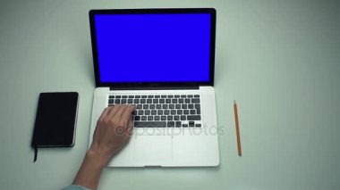 Üstten Görünüm erkek ellerini beyaz masada yeşil ekranlı dizüstü bilgisayar kullanan