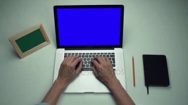 Beyaz masa yeşil ekranlı dizüstü bilgisayar kullanan ofis çalışanı