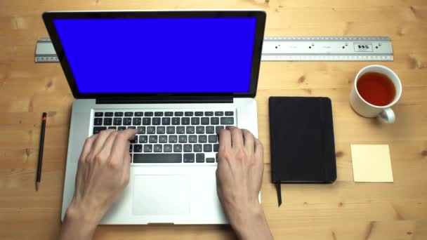 Männliche Hände bedienen Laptop mit grünem Bildschirm am Holztisch. Bürobedarf — Stockvideo