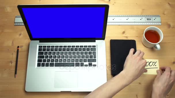 Bovenaanzicht mannelijke handen plakken op plaknotities op laptop met groen scherm. — Stockvideo