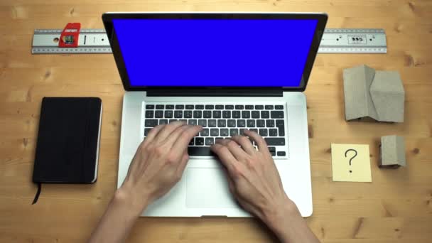 Young man using laptop with green screen at wooden desk. Top view on male hands — Stock Video