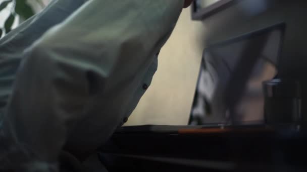 Junger Mann mit Laptop in der Küche. Wasserglas, Notizblock und Bleistift auf Tisch — Stockvideo