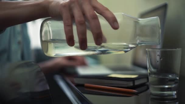 Mano masculina vertiendo agua en el vidrio en la cocina. Freelancer trabajando en casa — Vídeos de Stock