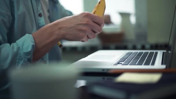 Επιχείρηση άνθρωπος τρώει μπανάνα χρησιμοποιούν φορητό υπολογιστή στο σπίτι. Ο άνθρωπος που εργάζονται εκτός γραφείου. — Αρχείο Βίντεο