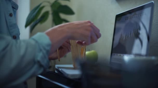 Freelancer usando laptop comiendo plátano en casa. Joven trabajando fuera de la oficina — Vídeos de Stock