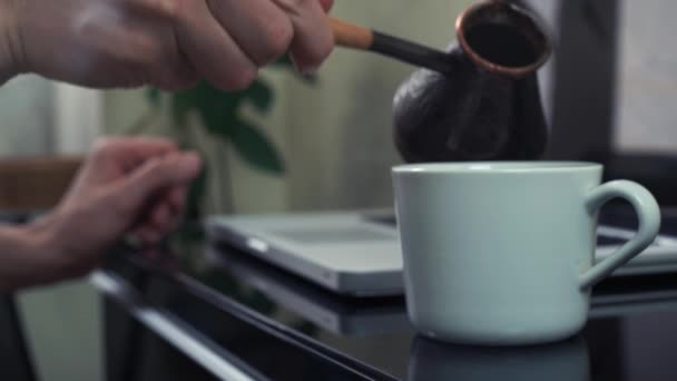 Handen van de jonge man gieten dampende koffie in beker op keuken. — Stockvideo