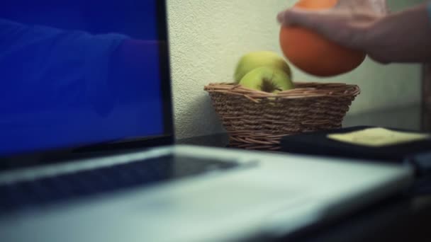 Manos masculinas tomando naranja usando el ordenador portátil con pantalla verde en casa . — Vídeos de Stock