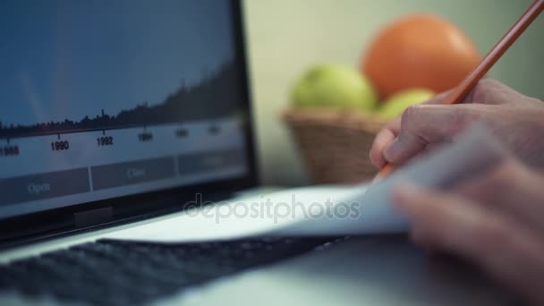 年轻人在家里使用笔记本电脑。笔记本电脑屏幕上的图形分析. — 图库视频影像