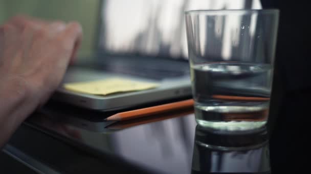 Les mains masculines sur le clavier. Verre d'eau et crayon sur la table. Plan rapproché .