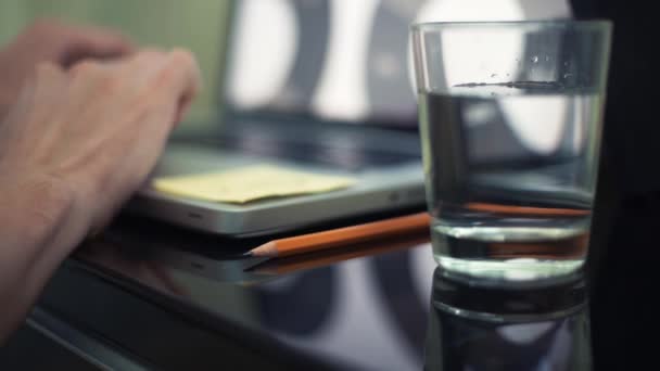 Gros plan de verre d'eau et crayon sur la table. Jeune homme utilisant un ordinateur portable dans un café .
