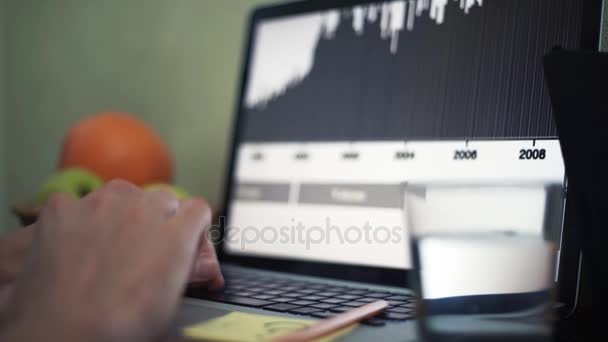 Jonge man met laptop in café. Glas water, Blocnote en potlood op tafel — Stockvideo