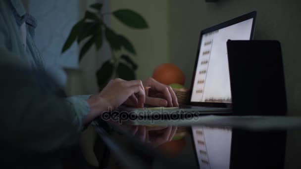 Rukou mladého muže na klávesnici notebooku. Sklenice vody a tužka na stole — Stock video
