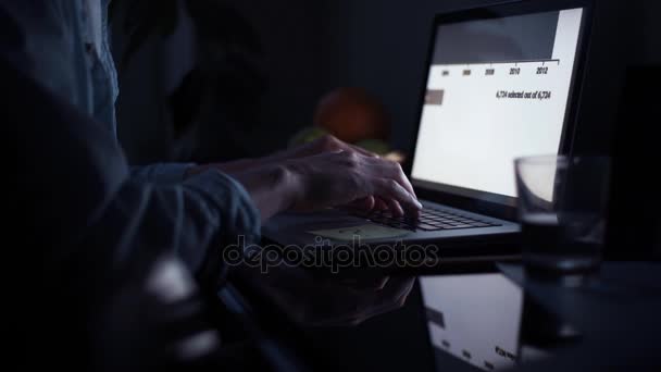 笔记本电脑键盘上的年轻男子的手。一杯水和一张桌子上的铅笔 — 图库视频影像
