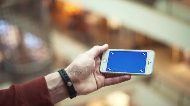 Adam el ile alışveriş merkezi mavi perde smartphone kullanarak