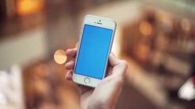 Erkek el ile alışveriş merkezinde mavi perde smartphone kullanarak