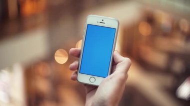 Adam el ile alışveriş merkezinde mavi perde smartphone kullanarak