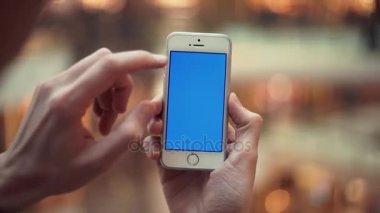 Erkek silah ile alışveriş merkezinde mavi perde smartphone kullanarak