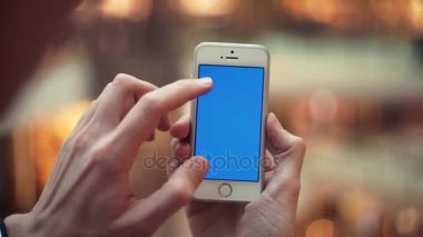 Adam silah ile alışveriş merkezinde mavi perde smartphone kullanarak