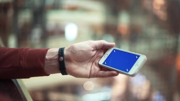 Male hands using smartphone with blue screen in shopping mall — Stock Video