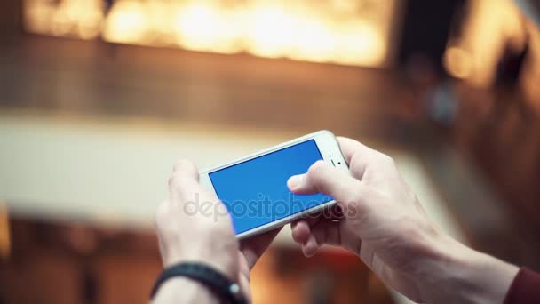 Brazos de hombre usando teléfono inteligente con pantalla azul en el centro comercial — Vídeo de stock