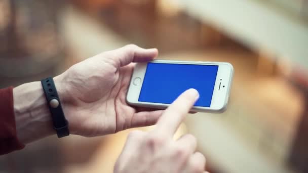 Manos de hombre usando teléfono con pantalla azul en el centro comercial — Vídeo de stock