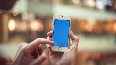 Alışveriş merkezinde mavi ekran ile telefon kullanarak adam eller