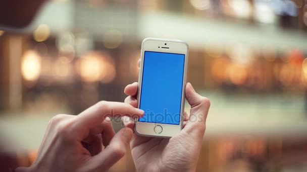 Manos de hombre usando teléfono con pantalla azul en el centro comercial — Vídeo de stock