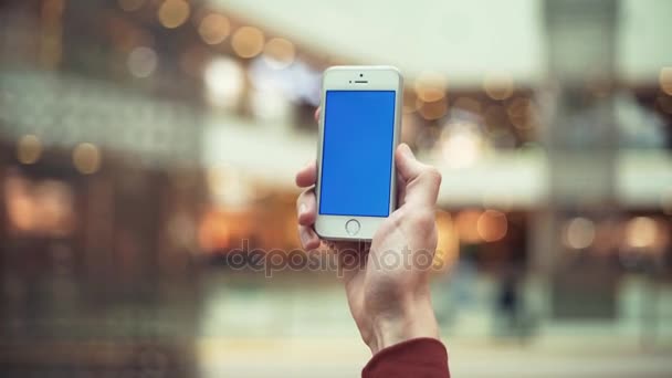 Männliche Arme mit Telefon mit blauem Bildschirm in Einkaufszentrum — Stockvideo