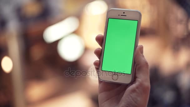 Les mains de l'homme utilisant le téléphone avec affichage vert dans le centre commercial 