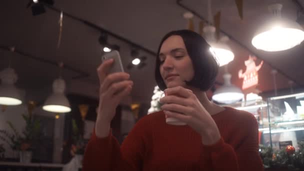 Attraktiv kvinna med smartphone tar selfie sitter i café. Juletid — Stockvideo