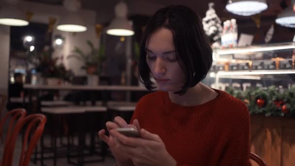 Mulher jovem bonito mensagem de texto usando smartphone sentado no café . — Vídeo de Stock