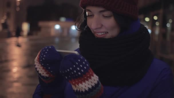 Glad ung kvinna ler med smartphone vaktande video står utomhus — Stockvideo