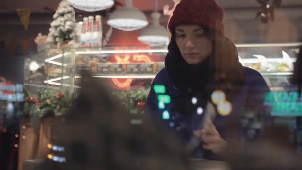 Joven chica bonita usando teléfono inteligente tomando fotos sentado dentro de la cafetería. Tiempo de Navidad — Vídeos de Stock