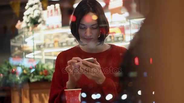 Mujer bastante joven riendo usando teléfono inteligente chat en línea sentado en la cafetería — Vídeos de Stock