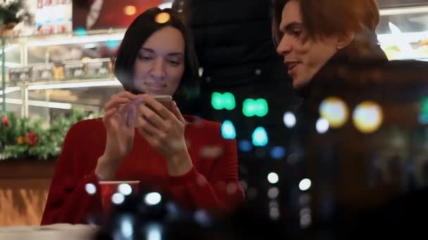 Junges Paar lächelt und erzählt von etwas, das abends im Café sitzt — Stockvideo