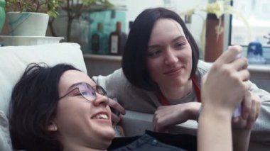 Genç kızlar kullanma Smartphone yalan gülüyor evde kanepe.