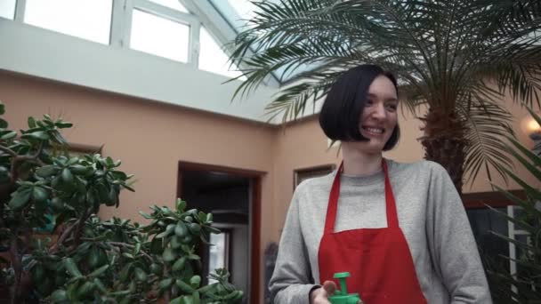 젊은 꽃 소녀 가정 정원에서 분무기와 식물을 급수의 초상화 — 비디오