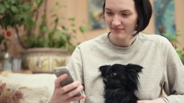 Smartphone vuruş şirin küçük chihuahua köpek serada kullanan genç kadın