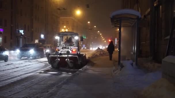 Ανθρώπους και τα αυτοκίνητα που κινούνται κατά μήκος της οδού τη νύχτα στο βαρύ χιόνι το χειμώνα. — Αρχείο Βίντεο