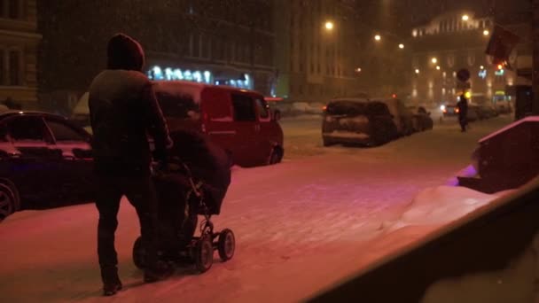 Ludzie i samochody poruszające się po ulicy w nocy w ciężki śnieg w zimie. — Wideo stockowe