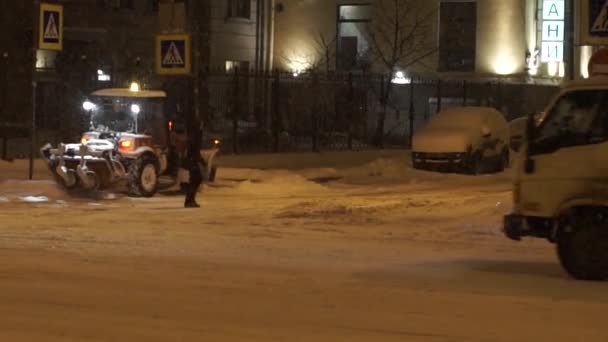 Personas y coches moviéndose a lo largo de la calle por la noche en la nieve pesada en invierno . — Vídeo de stock