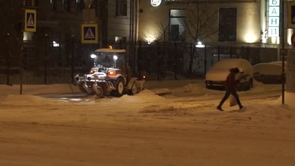 Les gens et les voitures se déplaçant le long de la rue la nuit dans la neige épaisse en hiver . — Video