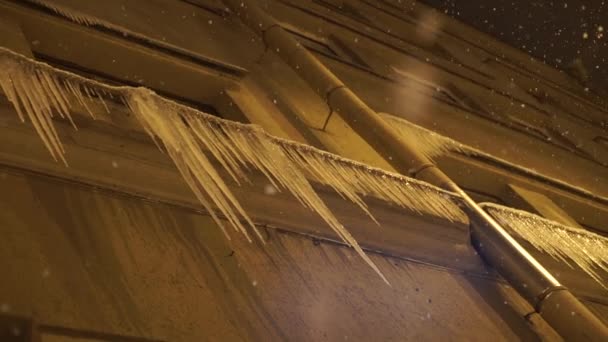 Gefährliche Eiszapfen hängen vom verschneiten Dach des Gebäudes — Stockvideo