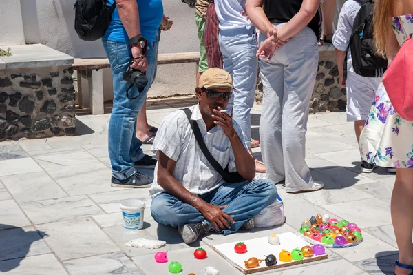 Yunanistan, Santorini üzerinde 24 Haziran 2015. Prodovets adam oturur ve bir sigara içen Hediyelik eşya